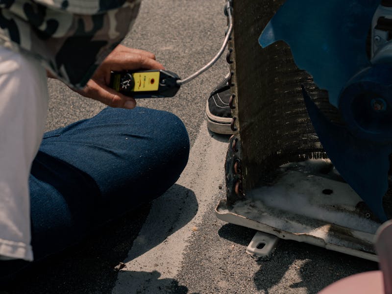 Technician testing air conditioning system performance with multimeter
