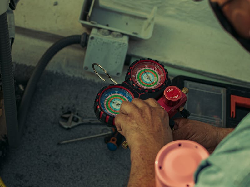 AC maintenance technician checking refrigerant levels with a pressure gauge