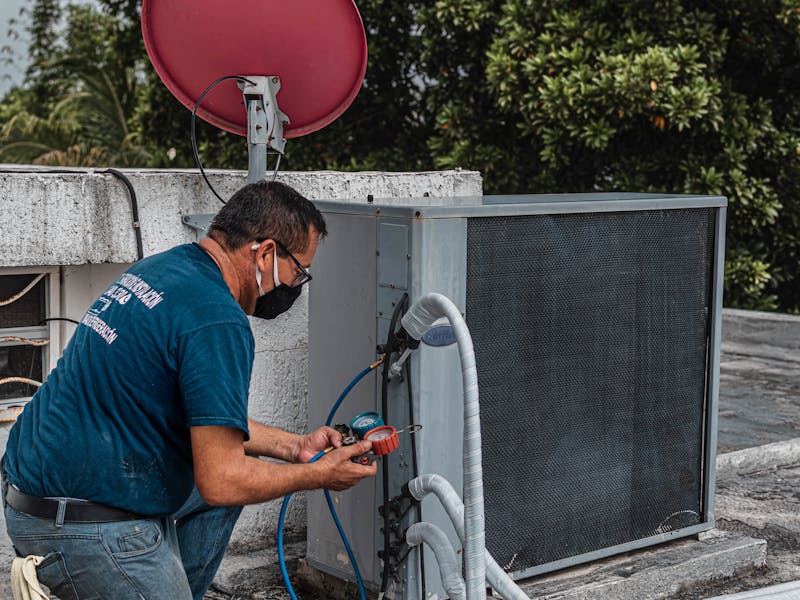 Heating system repair technician diagnosing furnace issues with manifold gauge